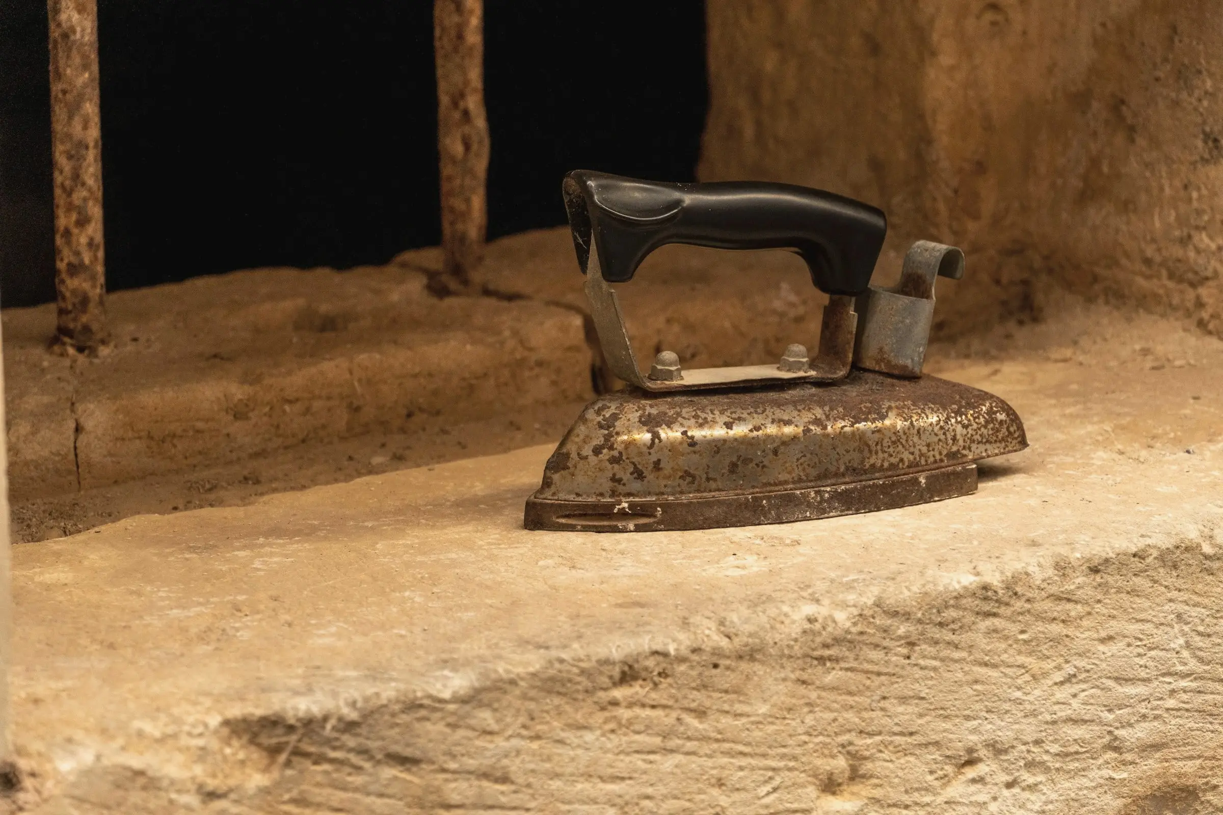 An antique cast-iron press resting on a worn stone slab